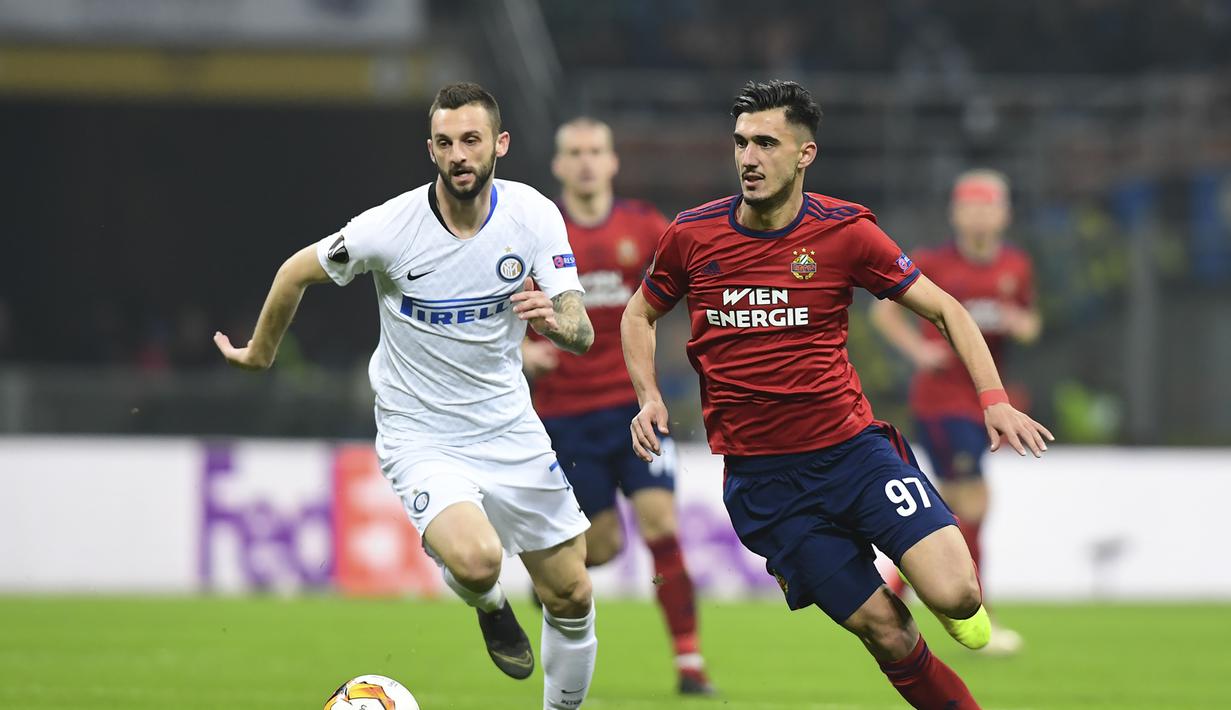 Gelandang Rapid Wien, Andrei Ivan melewati Marcelo Brozovic pada leg 2, babak 16 besar Liga Europa yang berlangsung di stadion Giuseppe Meazza, Milan, Jumat (22/2). Inter Milan menang 4-0 atas rapid Wien. (AFP/Miguel Medina)