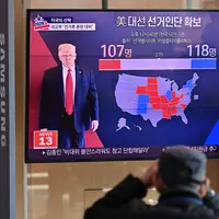 Orang-orang menonton program berita televisi tentang pemilihan presiden (pilpres) AS yang menampilkan gambar Presiden Donald Trump (kiri) dan calon presiden dari Partai Demokrat Joe Biden (kanan), di sebuah stasiun kereta api di Seoul, Korea Selatan pada Rabu (4/11/2020). (Photo by Jung Yeon-je/AFP)