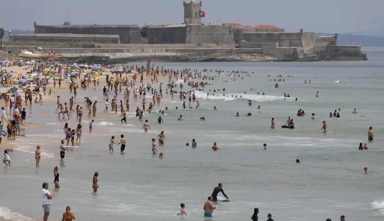 Pengunjung pantai menikmati air di Pantai Carcavelos, di luar Lisbon, Selasa (12/7/2022). Portugal mengalami gelombang panas yang membuat pemerintah mengumumkan keadaan siaga mulai Senin hingga Jumat karena meningkatnya risiko kebakaran hutan. (AP Photo/Armando Franca)
