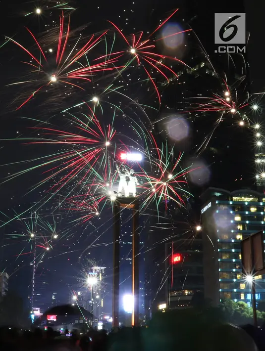 Kembang api menghiasi malam pergantian tahun baru 2019 di kawasan Bundaran HI, Jakarta, Selasa (1/1). Bundaran HI menjadi salah satu pilihan warga menikmati kembang api tahun baru. (Liputan6.com/Angga Yuniar)