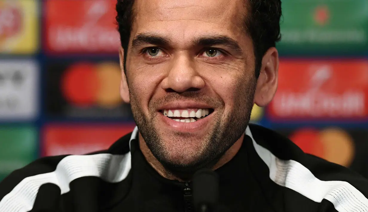 Bek Paris Saint-Germain Dani Alves tersenyum saat konferensi pers di stadion Parc des Princes di Paris (4/3). PSG akan bertanding pada leg kedua babak 16 besar Liga Champions melawan tim Spanyol, Real Madrid di Prancis. (AFP Photo/Franck Fife)