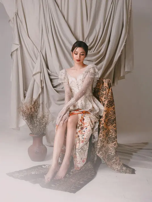 Mikha Tambayong kenakan kebaya modifikasi yang apik. Bagian atasnya dipenuhi renda, bordir, dan payet putih. Dipadukan dengan kain batik warna cream. [Instagram/miktambayong]