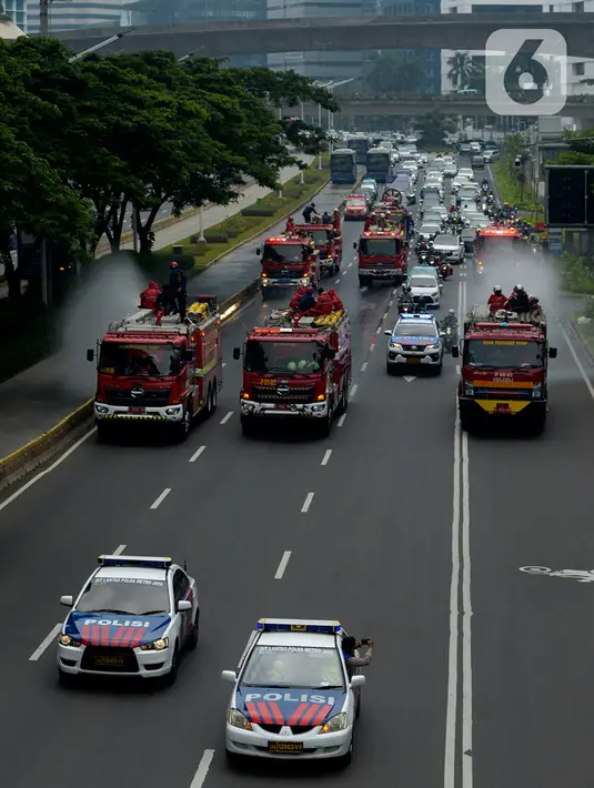 Petugas pemadam kebakaran (Damkar) dengan mobil pemadam melakukan penyemprotan cairan disinfektan di sepanjang jalan Thamrin-Sudirman, Jakarta, Sabtu (28/3/2020). Penyemprotan dilakukan untuk meminimalisir penyebaran COVID-19 di ruang udara dan ruas jalan. (merdeka.com/Imam Buhori)