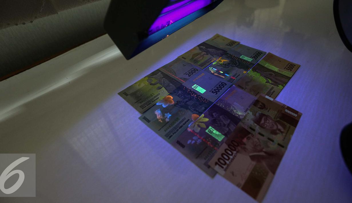 Gambar uang kertas rupiah disinari lampu ultraviolet di kantor Peruri, Karawang, Jawa Barat, Rabu (18/1). Rupiah memiliki sistem pengamanan tiga level dan menjadi mata uang yang pengamanannya sangat kompleks. (Liputan6.com/Faizal Fanani)