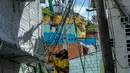 Seorang pria mengecat dinding bangunan di kawasan kumuh El Pesebre, pinggiran kota Medellin, Kolombia, 19 Juni 2017. Seniman Prancis, Tarik Bouanani melukis 230 rumah di kawasan tersebut membentuk mural raksasa. (JOAQUIN SARMIENTO/AFP)