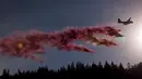 Sebuah pesawat pemadam kebakaran menyemprotkan sebuah cairan ke lokasi kebakaran hutan Nasional Sierra di California, AS, Jumat (21/8/2015). Kebakaran ini menciptakan kepulan asap hingga ketinggian ratusan meter ke angkasa. (REUTERS/Max Whittaker)