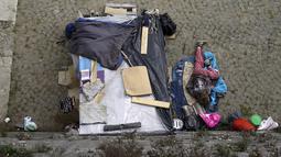 Seorang tunawisma tertidur di samping tendanya di kawasan permukiman kumuh bawah jembatan di Sungai Tiber, Roma, Italia (13/4). Kondisi tempat tinggal para tunawisma tersebut tak jauh beda dengan di Jakarta. (REUTERS / Max Rossi)