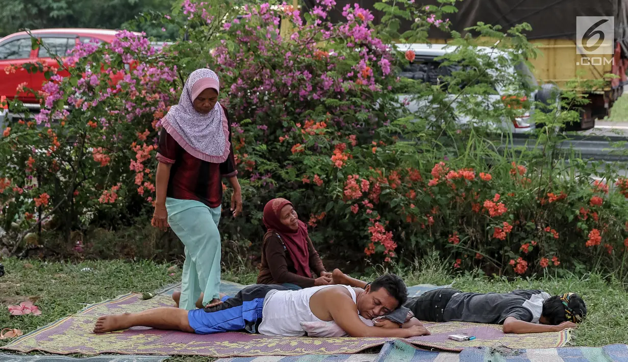 Pemudik memanfaatkan jasa terapis pijat dadakan dari warga sekitar di rest area Tol Palimanan - Kanci, Cirebon, Jawa Barat, Sabtu (1/7). Selama lebaran warga sekitar memanfaatkan arus balik dengan menyediakan jasa pijat. (Liputan6.com/Faizal Fanani)