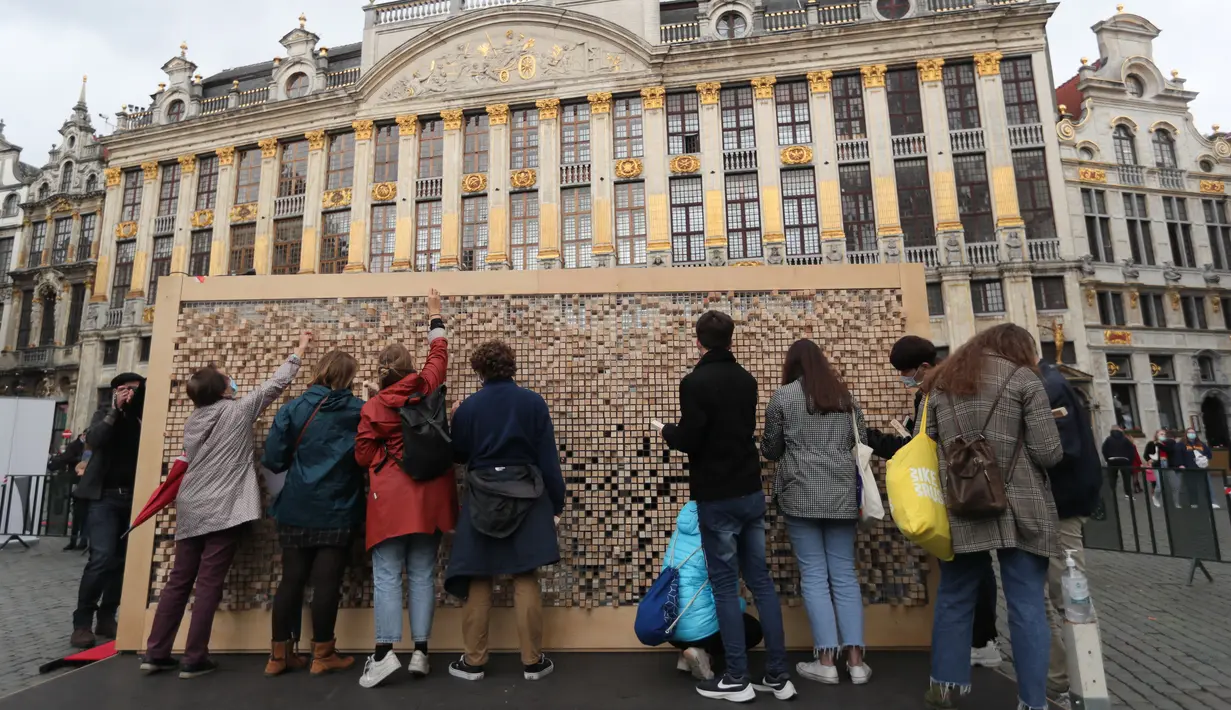 Orang-orang mengambil sejumlah balok kayu dari "The Disappearing Wall" di Grand Place, Brussel, Belgia, 3 Oktober 2020. Instalasi seni memperingati 30 tahun reunifikasi Jerman itu terdiri dari 6.000 balok kayu dilengkapi kutipan para seniman dan pemikir dari seluruh dunia. (Xinhua/Zheng Huansong)