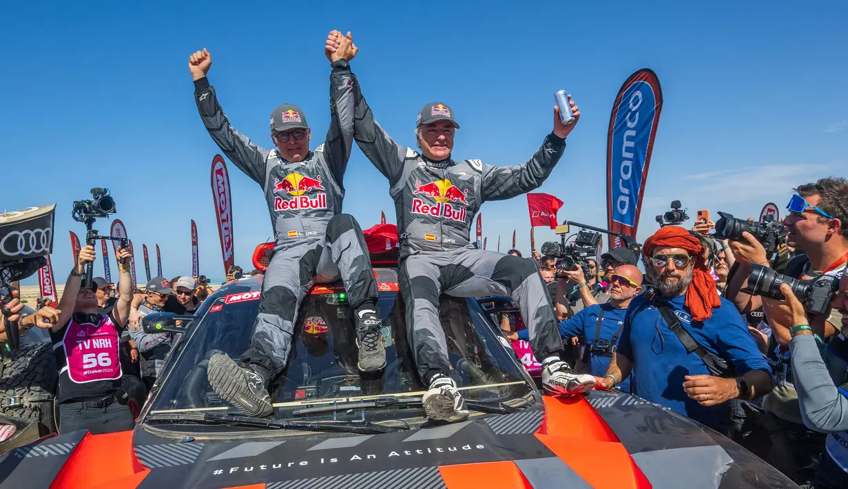 Pembalap Team Audi Sport, Carlos Sainz (kanan) dan co-driver, Lucas Cruzof merayakan kemenangan setelah menyelesaikan etape terakhir Reli Dakar 2024 di Yanbu, Arab Saudi, Jumat, 19 Januari 2024 waktu setempat. (AFP/Patrick Hertzog)