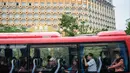 Wisatawan duduk dalam bus dengan latar belakang resor kasino Grand Lisboa (kiri) di Macau, 5 Maret 2019. Macau saat ini memiliki lebih dari 30.000 kamar tamu yang tersebar di 75 properti hotel bintang dua hingga lima. (Anthony Wallace/AFP)