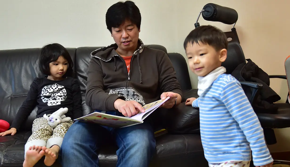 Kim Jin-Sung membacakan buku untuk putrinya Na-Eun dan putranya Won-Woo di apartemen mereka di Seoul. Sebuah ide yang tak biasa dimana anak sehari-hari dapat diurus oleh seorang pria yang merupakan tanggung jawab wanita. (AFP PHOTO/JU)