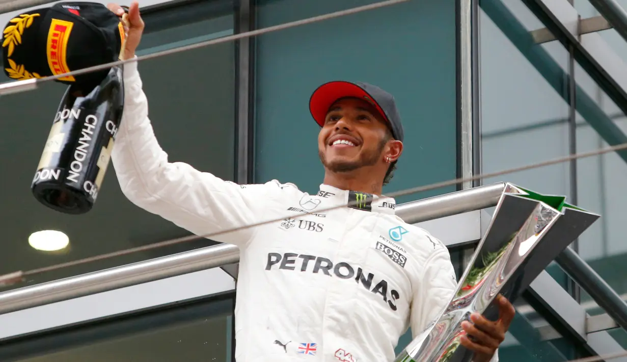 Pembalap Mercedes, Lewis Hamilton bersorak sambil memegang trofi Grand Prix (GP) China di Sirkuit Internasional Shanghai, Minggu (9/4). Hamilton finis pertama dengan catatan waktu 1 jam 37 menit 36,158 detik.(AP Photo/Toru Takahashi)