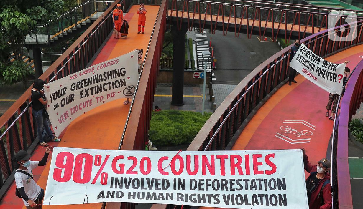 Sejumlah aktivis yang tergabung dalam Extintion Rebellion (XR) dan Walhi Jakarta melakukan aksi di JPO Pinisi, Jalan Jenderal Sudirman, Jakarta, Senin (14/11/2022). Aksi tersebut dilakukan untuk menyerukan kepada para pemimpin agar menghentikan “pencucian hijau” dan praktik ekonomi “business-as-usual” yang secara sistematis memperburuk krisis iklim dan mendorong umat manusia pada kehancuran ekologis & kepunahan massal. Negara-negara G20 turut menyumbang atas 80 persen emisi karbon dunia dan 60 persen populasi penduduk bumi. (Liputan6.com/Angga Yuniar)