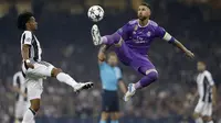 Kapten Real Madrid, Sergio Ramos, mengamankan bola dari gelandang Juventus, Juan Cuadrado, pada laga final Liga Champions di Stadion Stadion Millenium, Cardiff, Sabtu (3/6/2017). Madrid menang 4-1 atas Juventus. (AFP/Adrian Dennis)