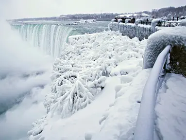 Pengunjung mengabadikan pemandangan Horseshoe Falls di Air Terjun Niagara yang membeku di Ontario, Kanada, Jumat (29/12). Cuaca dingin melanda sebagian besar wilayah utara Amerika Serikat di akhir tahun ini. (Aaron Lynett/Canadian Press via AP)