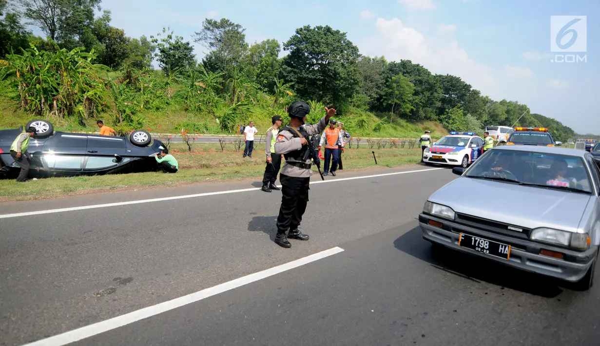 Petugas mengatur lalu lintas di lokasi terbaliknya sebuah mobil di KM 208 Tol Palikanci (Palimanan-Kanci), Jawa Barat, Rabu (21/6). Pengemudi mobil bernopol B 2247 TKL itu diduga mengantuk hingga mengakibatkan mobil terbalik. (Liputan6.com/Gempur M Surya)