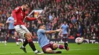 Pemain MU, Bruno Fernandes (kiri), menendang bola ke gawang Aston Villa yang membuahkangol dalam pertandingan pekan ke-34 Liga Inggris 2022/2023 yang berlangsung di Old Trafford, Minggu (30/4/2023). (AFP/Oli Scarff)