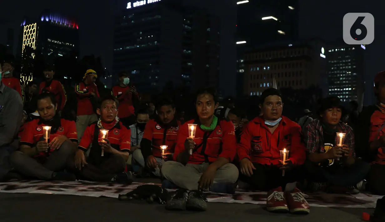 Beberapa peserta aksi unjuk rasa memegang lilin saat doa bersama lintas agama di Kawasan Patung Kuda, Jakarta, Selasa (10/11/2020). Sejumlah massa gabungan dari berbagai organisasi buruh dan mahasiswa berunjuk rasa menolak pengesahan Omnibus Law UU Cipta Kerja. (Liputan6.com/Helmi Fithriansyah)