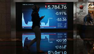 Pekerja melintasi layar pergerakan Indeks Harga Saham Gabungan (IHSG) di BEI, Jakarta, Rabu (16/5). Meski terjebak di zona merah, IHSG berhasil mengakhiri perdagangan di level 5.841. (Liputan6.com/Angga Yuniar)