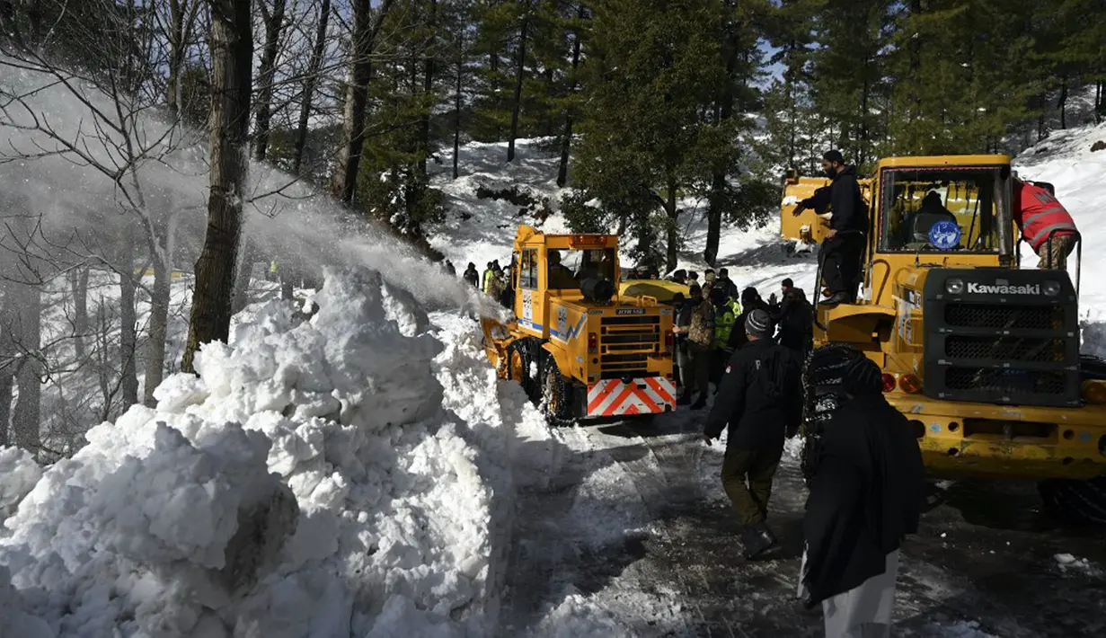 Para pekerja menggunakan alat berat untuk membersihkan jalanan usai badai salju menjebak kendaraan wisatawan di sepanjang jalan Bukit Murree, Pakistan, 9 Januari 2022. Sebanyak 22 wisatawan tewas saat sekitar 1.000 kendaraan terjebak salju tebal di Bukit Murree. (Aamir QURESHI/AFP)