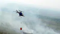 Helikopter menjatuhkan air di atas lahan gambut yang terbakar di Kabupaten Pelalawan, Riau. Dephut mengirim helikopter Mabes Polri untuk menanggulangi kebakaran lahan dan hutan.(Antara)