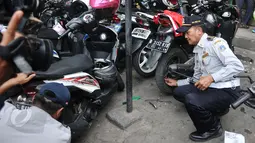 Petugas mencopot pentil motor saat melakukan razia parkir liar di kawasan Tanah Abang, Jakarta, Rabu (3/6/2015). Meski sudah disosialisasikan, kenyataannya masih banyak orang yang tak menghiraukan peraturan tersebut. (Liputan6.com/Johan Tallo)