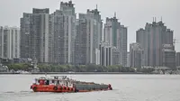 Kapal berlayar di sepanjang Sungai Huangpu di distrik Pudong yang dikunci sebagai tindakan pencegahan Covid-19, di Shanghai (28/3/2022). Jutaan orang di China pusat keuangan dikurung di rumah ketika bagian timur Shanghai dikunci untuk mengekang Covid terbesar di negara itu. (AFP/Hector Retamal)