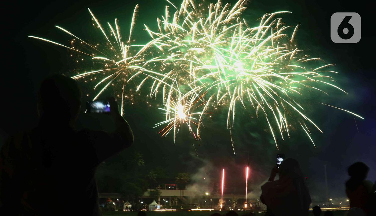 Warga menyaksikan pesta kembang api saat perayaan malam puncak Tahun Baru 2023 di Danau Archipelago, Taman Mini Indonesia Indah (TMII), Jakarta, Minggu (1/1/2023). Kembang api yang diluncurkan sangatlah indah dan beragam. Baik dari perpaduan warna, letupan, hingga perpaduan terbangnya yang beragam. (Liputan6.com/Herman Zakharia)