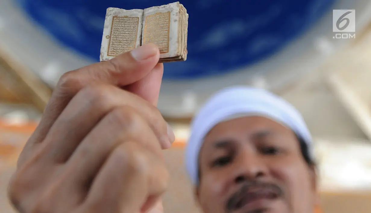 Kyai Tubagus Muhammad Tamyiz menunjukkan Alquran mini di Masjid Jami Darusalam, Sukaraja, Bogor, Kamis (24/5). Alquran mini itu seluruh aksaranya ditulis tangan menggunakan tinta emas serta ditulis di atas lembaran kulit kayu. (Merdeka.com/Arie Basuki)