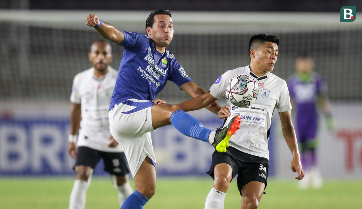 Pemain Persib Bandung, Ezra Walian (kiri) berebut bola dengan pemain Persipura Jayapura, Takuya Matsunaga dalam laga pekan ke-10 BRI Liga 1 2021/2022 di Stadion Manahan, Solo, Sabtu (30/10/2021). (Bola.com/Bagaskara Lazuardi)