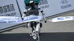 Sebuah robot melintasi garis finis dalam lomba lari setengah maraton robot humanoid di Beijing pada 19 April 2025. (Pedro PARDO/AFP)