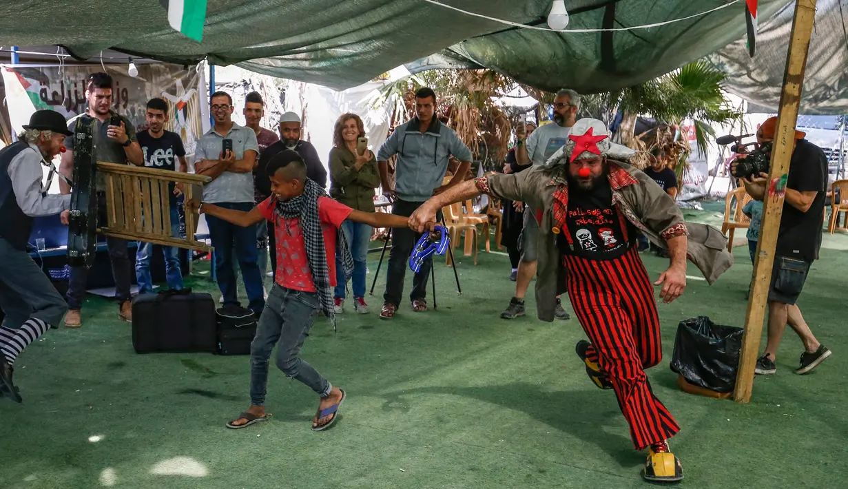 Rombongan badut Spanyol menghibur anak-anak Palestina di desa suku Bedouin, Tepi Barat yang diduduki, 22 September 2018. Atraksi ini dilakukan lantaran desa berpenduduk sekitar 180 orang itu akan digusur Israel pada Oktober mendatang. (AFP/ABBAS MOMANI)