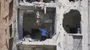 Seorang wanita berjalan melewati apartemennya yang rusak akibat serangan Israel di kota Pelabuhan Tyre, Lebanon Selatan, Kamis 18 Juni 2026. (AP Photo/Hassan Ammar)