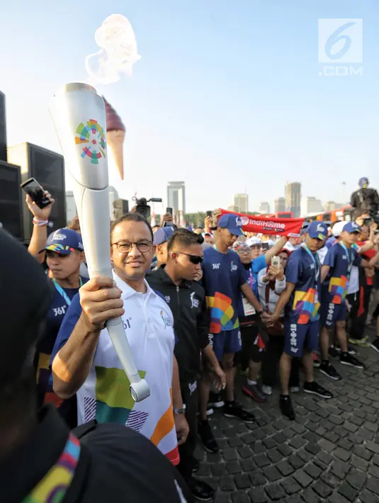 Gubernur DKI Jakarta Anies Baswedan membawa obor Asian Games 2018 di Jakarta, Sabtu (18/8). Anies berlari sepanjang 100 meter membawa obor Asian Games 2018. (Liputan6.com/Faizal Fanani)