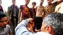 Seorang pria Yaman mengoleskan kosmetik tradisional kohl ke kelopak mata pria lain di Masjid Agung, kota tua Sanaa pada 9 mei 2019. Bagi muslim Yaman, pemakaian kohl diyakini mampu membersihkan dan melindungi mata dari penyakit ini sudah menjadi tradisi setiap bulan Ramadan. (MOHAMMED HUWAIS/AFP)