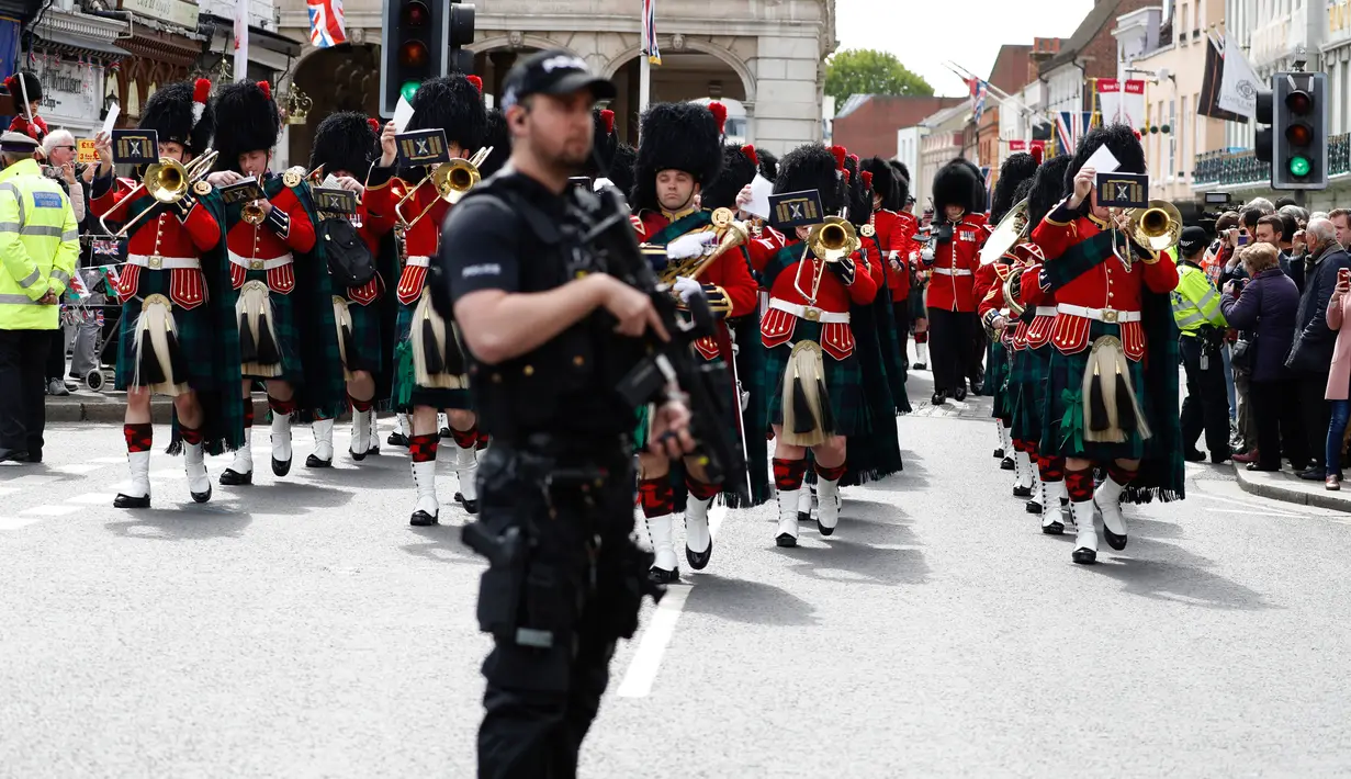 Polisi menjaga Resimen Kerajaan Skotlandia saat berbaris di jalan raya memperingati kelahiran anak pertama Pangeran Harry dan Meghan Markle di Windsor, Inggris, Selasa (7/5/2019). Pangeran Harry menyatakan bahwa dia dan Meghan Markle masih memikirkan nama anak mereka. (AP Photo/Alastair Grant)