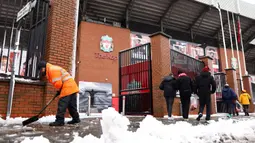 Seorang petugas membersihkan salju di sekitar area Stadion Anfield menjelang laga lanjutan Liga Inggris 2024/2025 antara Liverpool melawan Manchester United pada Minggu (05/01/2025). (AFP/Darren Staples)