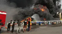 Warga membantu petugas pemadam menjinakkan api yang membakar gudang di Jalan Kampung Bandan, Ancol, Jakarta Utara, Kamis (5/7). Tujuh mobil damkar didatangkan dari pemadam kebakaran Jakarta Barat dan 10 dari Jakarta Pusat. (Kapanlagi.com/Budy Santoso)
