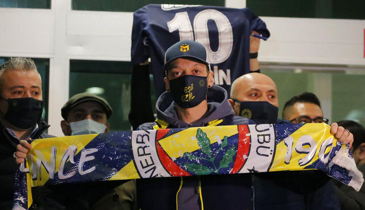 Pesepak bola asal Jerman, Mesut Ozil, menunjukan syal Fenerbahce saat tiba di Bandara Ataturk, Turki, Senin (18/1/2021). Setelah memutuskan hengkang dari Arsenal, Ozil akan memperkuat klub asal Turki, Fenerbahce. (AP Photo)