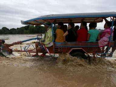 Warga Filipina mengunakan traktor menyebrangi banjir usai hujan lebat di Kota Candaba, Pampanga, Manila, Filipina (17/12). Sembilan orang tewas akibat bencana yang terjadi di Filipina. (REUTERS/Romeo Ranoco)