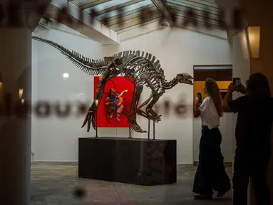 Pengunjung melihat kerangka Barry, spesimen besar Camptosaurus dari akhir periode Jurassic, yang dipajang sebelum dilelang di galeri Georges-Philippe & Nathalie Vallois, Paris, Senin (18/9/2023). (Dimitar DILKOFF / AFP)