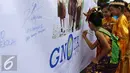 Sejumlah anak menuliskan testimoni saat Festival Anak Asuh di Car Free Day, Jakarta, Minggu (1/11/2015). Festival ini diikuti 200 lebih anak asuh dari SDN Kebon Sirih. (Liputan6.com/Yoppy Renato)