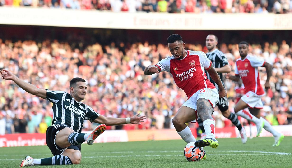 Pemain Arsenal, Gabriel Jesus (kanan), berhasil mengecoh pemain MU, Diogo Dalot dan mencetak gol ketiga bagi Arsenal ke gawang MU dalam pertandingan pekan keempat Liga Inggris 2023/2024 yang berlangsung di Emirates Stadium, London, Senin (4/9/2023) dini hari WIB. (AFP/Glyn Kirk)