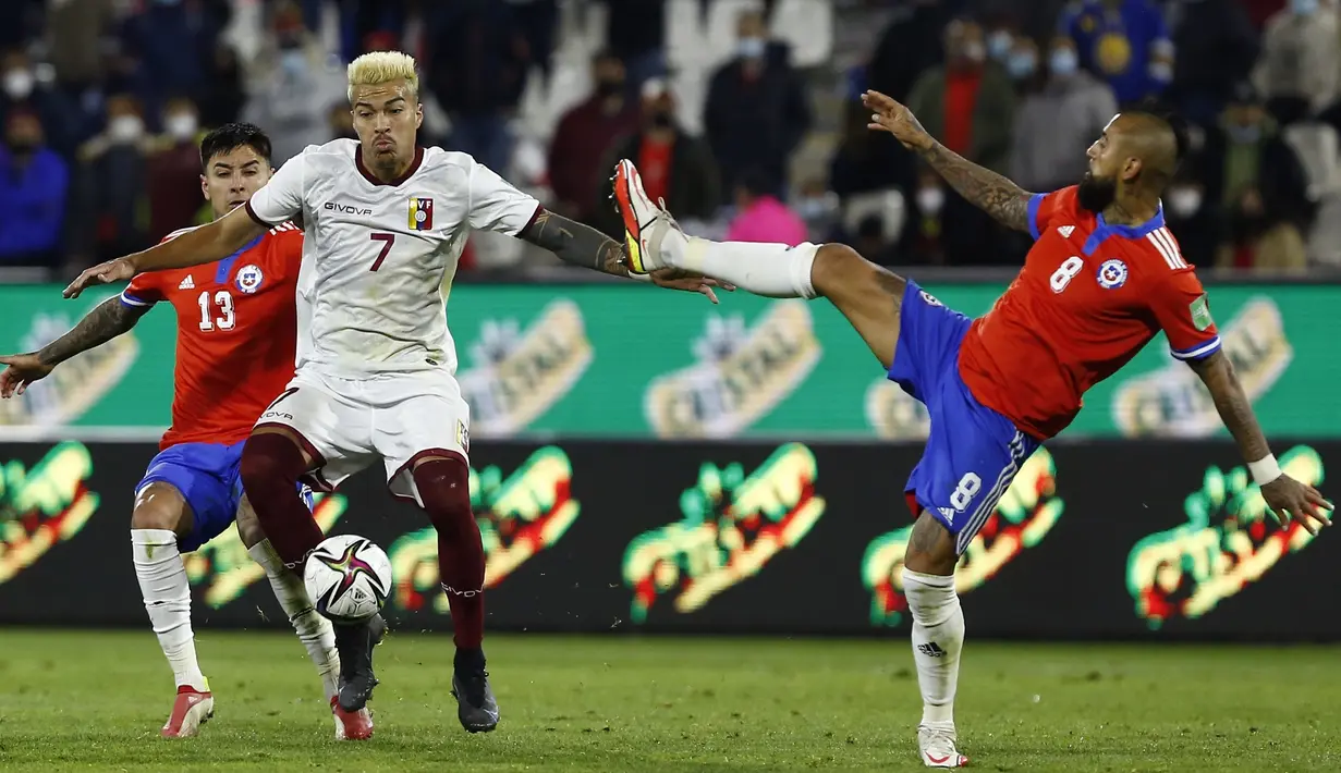 Pemain Venezuela Adalberto Penaranda (tengah) berebut bola dengan pemain Chile Erick Pulgar (kiri) dan Arturo Vidal pada pertandingan kualifikasi Piala Dunia 2022 di Stadion San Carlos de Apoquindo, Santiago, Chile, Kamis (14/10/2021). Chile menang 3-0. (Marcelo Hernandez/Pool via AP)