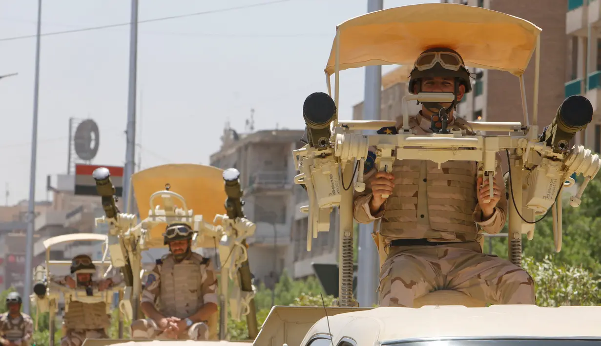 Pasukan Irak berada di atas mobil saat mengikuti parade militer di Baghdad, Irak (12/7). Mulai dari tank, roket, meriam hingga peralatan tempur unggulan lainnya dipamerkan selama parade militer tersebut. (REUTERS/Khalid al Mousily)