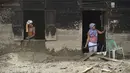 Tim gabungan berupaya mempercepat pembersihan material sisa bencana banjir bandang untuk memulihkan fungsi lingkungan dan akses publik. Tampak dalam foto, dua warga desa membersihkan rumah mereka yang rusak akibat banjir bandang di Desa Aek Garoga, Tapanuli Selatan, Sumatera Utara, pada Sabtu 27 Desember 2025. (YT Hariono /AFP)