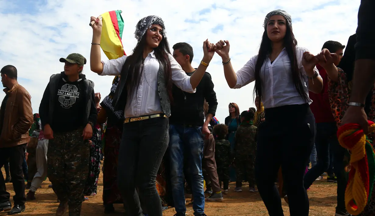 Dua wanita kurdi Suriah menari merayakan Perayaan Newroz di Kota Qamishli, Suriah (21/3).Newroz, juga dikenal sebagai Nawroz atau Nowruz adalah sebuah Festival Tahun Baru Persia Kuno. (AFP Photo / Delil Souleiman)