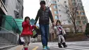 Gambar ini diambil pada 22 Desember 2015 menunjukkan seorang ayah dari Korea Selatan, Kim Jin-Sung (tengah) berjalan bersama putrinya Na-Eun dan Won-Woo pulang dari pusat penitipan anak di Seoul. (AFP PHOTO/JU)