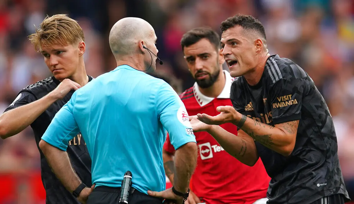 Pemain Arsenal Granit Xhaka (kanan) berdebat dengan wasit Paul Tierney saat melawan Manchester United pada pertandingan sepak bola Liga Premier Inggris di Stadion Old Trafford, Manchester, Inggris, 4 September 2022. Manchester United menang atas Arsenal dengan skor 3-1. (AP Photo/Dave Thompson)